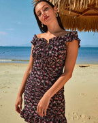 Woman wearing a floral ruffle dress on a tropical beach under a straw hut