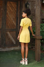 Lincoln Paris DaisyDay cotton linen dress hanging on a wooden hanger, showcasing a light, airy summer dress with floral patterns.