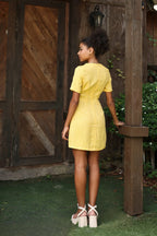 Lincoln Paris DaisyDay cotton linen dress hanging on a wooden hanger, showcasing a light, airy summer dress with floral patterns.
