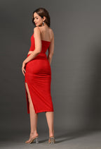 Woman in a fitted red midi dress with side slit and spaghetti straps, posing against gray backdrop