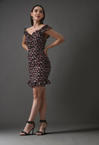 Woman wearing a ruffled off-shoulder floral mini dress with black heels in studio setting